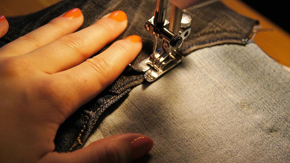 Sorgfältig näht man die Jeans zusammen. Sorgfältig näht man die Jeans zusammen.