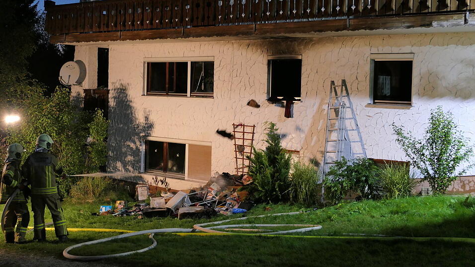 Aus dem Fenster werfen Feuerwehrleute mit Atemschutzmasken s&auml;mtliches Inventar heraus und Kameraden l&ouml;schen es sofort ab.