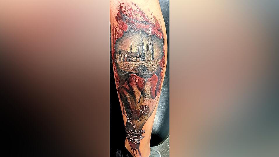 Klaus Köglmeier (44) aus Wenzenbach hat auch ein Heimattattoo. Das Motiv ist eine Zombiehand, die durch die aufgerissene Wunde den Regensburger Dom und die Steinerne Brücke zeigt: 'Ich bin dem Zombie-Genre verfallen, was auch meine Tattoos widerspiegeln. Ich wollte die Liebe zu Regensburg und zu Zombies in diesem Tattoo vereinen.' Gestochen wurde das Tattoo im Herbst 2021 und dauerte knapp zehn Stunden. Klaus Köglmeier (44) aus Wenzenbach hat auch ein Heimattattoo. Das Motiv ist eine Zombiehand, die durch die aufgerissene Wunde den Regensburger Dom und die Steinerne Brücke zeigt: 'Ich bin dem Zombie-Genre verfallen, was auch meine Tattoos widerspiegeln. Ich wollte die Liebe zu Regensburg und zu Zombies in diesem Tattoo vereinen.' Gestochen wurde das Tattoo im Herbst 2021 und dauerte knapp zehn Stunden.