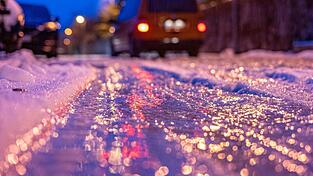 Eine dünne Eisschicht überzieht am frühen Morgen eine Straße.