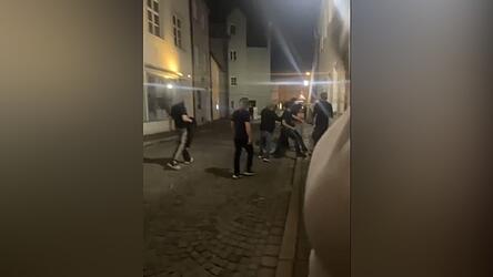 Die Gruppe stellt den 18-Jährigen an einer Hauswand. In dieser Aufnahme ist er verdeckt von einem Beteiligten. Zu sehen ist der gestreckte Arm eines Täters, der in Richtung Kopf schlägt. Die Gruppe stellt den 18-Jährigen an einer Hauswand. In dieser Aufnahme ist er verdeckt von einem Beteiligten. Zu sehen ist der gestreckte Arm eines Täters, der in Richtung Kopf schlägt.