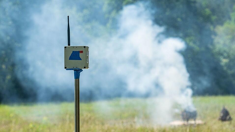 Ein Sensor zur Waldbrandfr&uuml;herkennung steht vor einem k&uuml;nstlich erzeugten Brand.