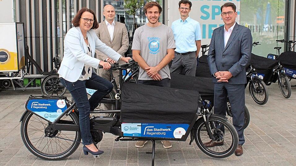 Gleich mal ausprobiert: (v.l.) Oberbürgermeisterin Gertrud Maltz-Schwarzfischer auf dem E-Lastenrad. Zusammen mit Mathis Broelmann (Stadtwerk), Christian Wenzl (Feine Räder), Thomas Großmüller (Nahmobilitätskoordinator Stadt Regensburg), Manfred Koller (Stadtwerk) präsentiert sie das neue Sharing. Gleich mal ausprobiert: (v.l.) Oberbürgermeisterin Gertrud Maltz-Schwarzfischer auf dem E-Lastenrad. Zusammen mit Mathis Broelmann (Stadtwerk), Christian Wenzl (Feine Räder), Thomas Großmüller (Nahmobilitätskoordinator Stadt Regensburg), Manfred Koller (Stadtwerk) präsentiert sie das neue Sharing.
