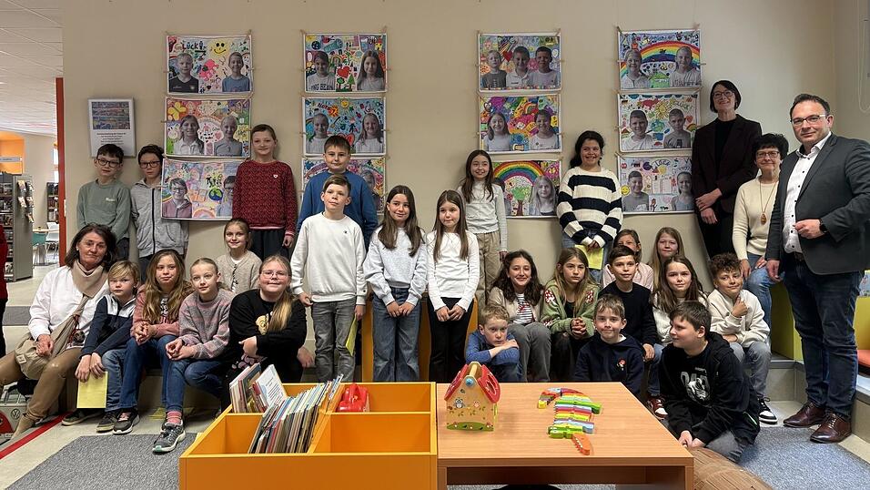 Die Sch&uuml;ler stehen stolz vor ihren Kunstwerken, die an der Wand in der Bilderbuchecke aufgeh&auml;ngt sind. Bis Ende des Schuljahres kann die Ausstellung von Interessierten besucht werden.