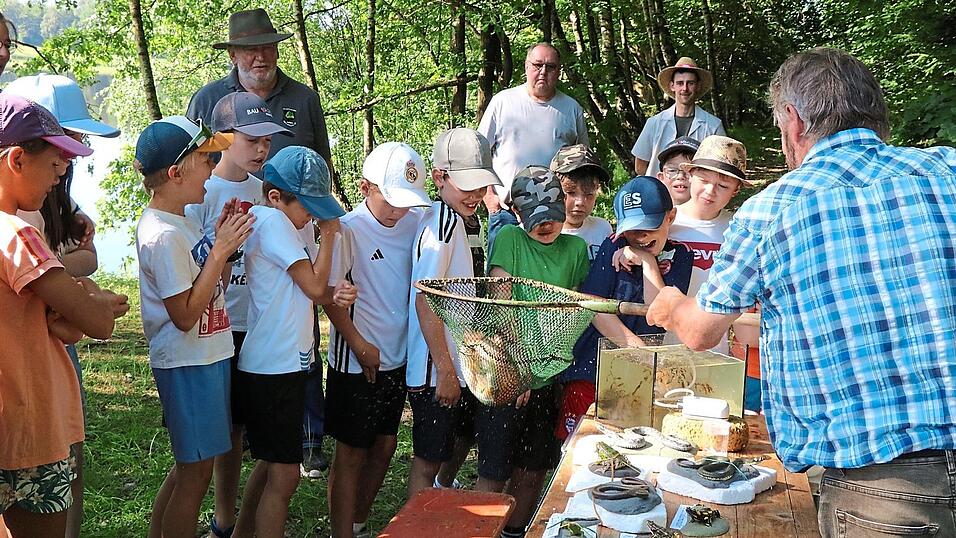 Franz Gebert (rechts) zeigt den M&auml;dchen und Buben eine Forelle; Mitglieder des Anglerbunds Waldm&uuml;nchen betreuen das Projekt &bdquo;Fischer machen Schule&ldquo;; auf dem Bild sind Helmut Danzer, Vorsitzender Thomas Althammer und Kassier Matthias Schneider (von links).