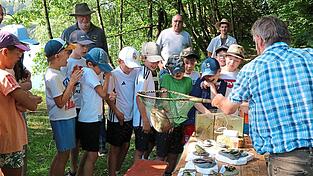 Franz Gebert (rechts) zeigt den M&auml;dchen und Buben eine Forelle; Mitglieder des Anglerbunds Waldm&uuml;nchen betreuen das Projekt &bdquo;Fischer machen Schule&ldquo;; auf dem Bild sind Helmut Danzer, Vorsitzender Thomas Althammer und Kassier Matthias Schneider (von links).