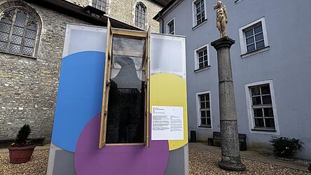 Oberhalb des Adlers auf drei S&auml;ulen sind Holzkunstwerke als W&auml;chter positioniert.