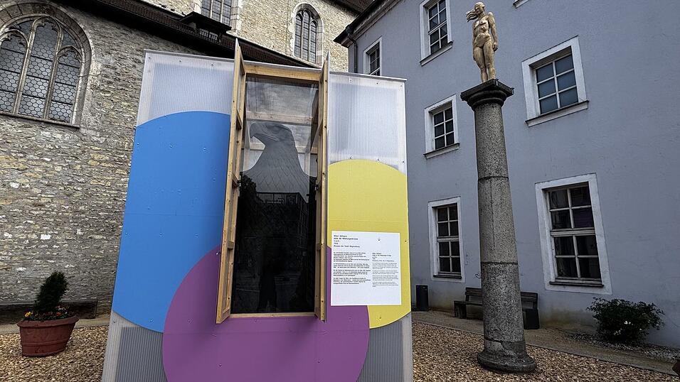 Oberhalb des Adlers auf drei S&auml;ulen sind Holzkunstwerke als W&auml;chter positioniert.