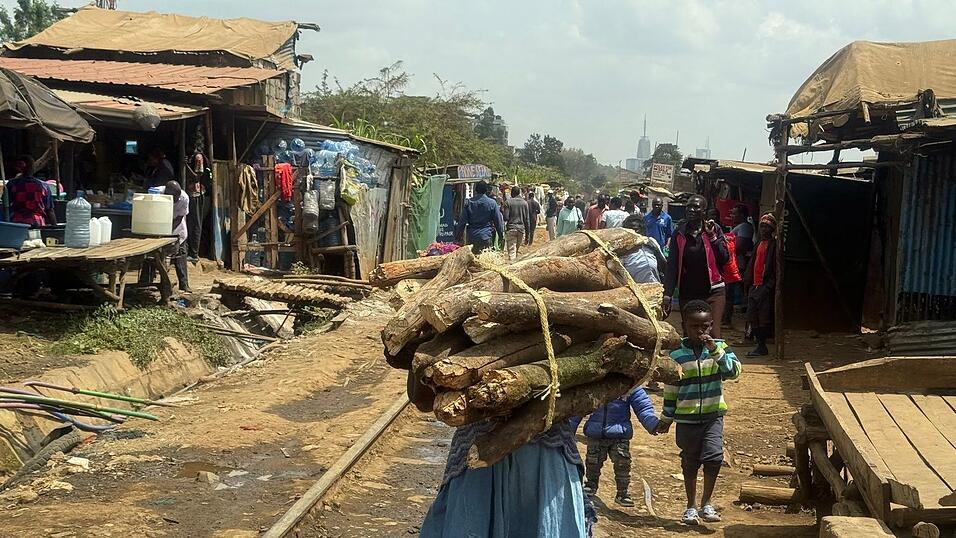 Eine Frau trägt ein Bündel Brennholz entlang der Bahnstrecke, die durch Nairobis größten Slum Kibera führt. (Archivbild) Eine Frau trägt ein Bündel Brennholz entlang der Bahnstrecke, die durch Nairobis größten Slum Kibera führt. (Archivbild)