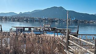 Gut getarnt hinter Pflanzen: Der ehemalige Ausflugsdampfer MS Bad Wiessee liegt auf dem Tegernsee bereits mit Wasser vollgelaufen schief am Steg. Das Landratsamt hat den Besitzer aufgefordert, ihn zu entfernen.