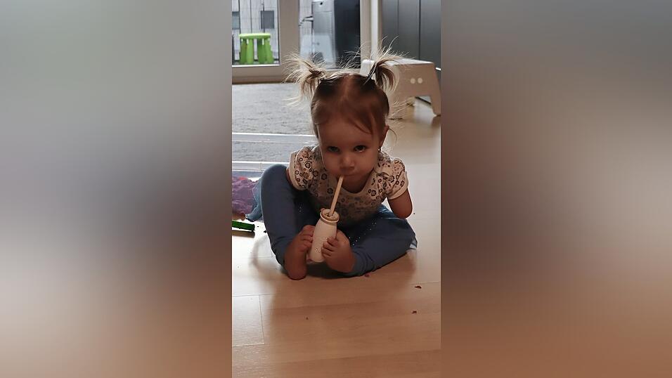 Mit ihren Zehen umklammert Leticia das Fl&auml;schen, um daraus zu trinken.