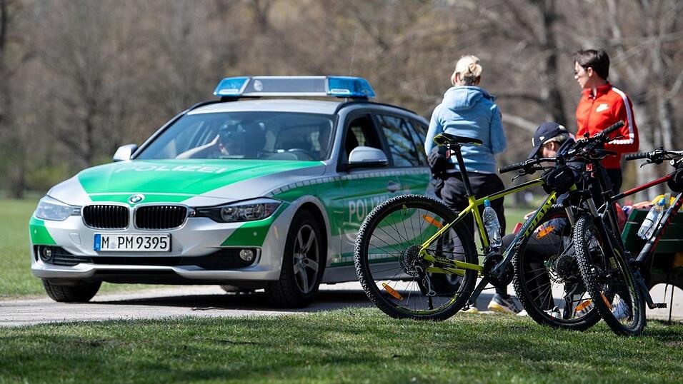 Polizisten kontrollieren im Englischen Garten Ausflügler, die auf einer Bank sitzen. Polizisten kontrollieren im Englischen Garten Ausflügler, die auf einer Bank sitzen.