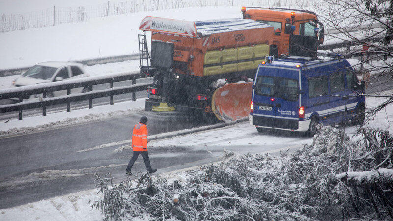 Ein Fahrzeug vom Winterdienst fährt auf der verschneiten Autobahn A8 bei Siegsdorf durch eine Engstelle, an der Bäume am Straßenrand umgefallen sind. Ein Fahrzeug vom Winterdienst fährt auf der verschneiten Autobahn A8 bei Siegsdorf durch eine Engstelle, an der Bäume am Straßenrand umgefallen sind.