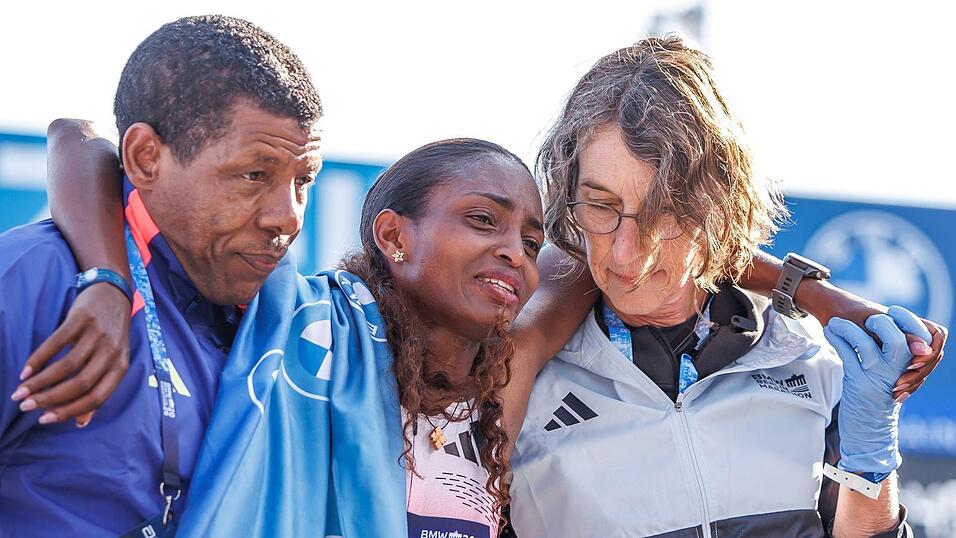Tigst Assefa musste mit Tränen in den Augen von Lauf-Legende und ihrem Trainer Haile Gebrselassie im Ziel gestützt werden. Tigst Assefa musste mit Tränen in den Augen von Lauf-Legende und ihrem Trainer Haile Gebrselassie im Ziel gestützt werden.