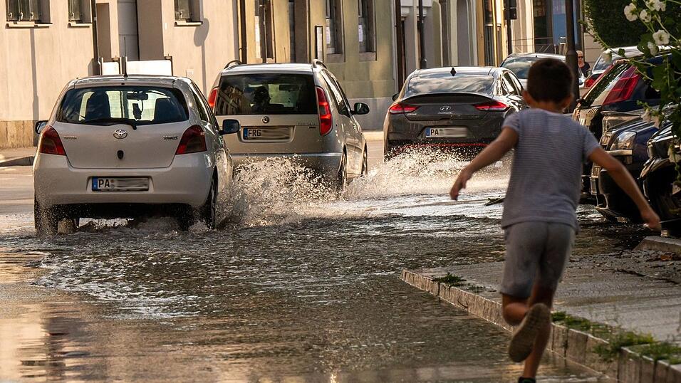 Ein Kind läuft in Passau über eine teilweise überflutete Straße Autos hinterher. Ein Kind läuft in Passau über eine teilweise überflutete Straße Autos hinterher.