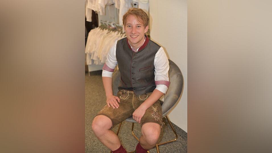 Das weiße Hemd hat rote Details. Dazu passt eine anthrazit-rote Weste. Die bordeauxroten Socken stimmen das Outfit farblich bis ins kleinste Detail ab.