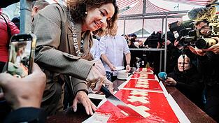 Amsterdams Bürgermeisterin Femke Halsema schneidet die lange Torte an. Amsterdams Bürgermeisterin Femke Halsema schneidet die lange Torte an.