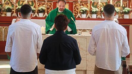 Adam und Ibrahim mit Maria Hertreiter (Mitte) vor dem Altar mit Dekan Jürgen Josef Eckl