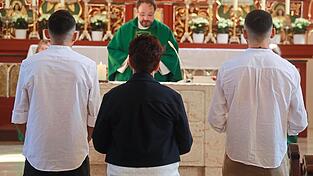 Adam und Ibrahim mit Maria Hertreiter (Mitte) vor dem Altar mit Dekan Jürgen Josef Eckl