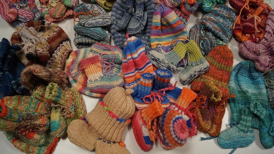 Ein stattliches Sortiment Mützchen und Söckchen häuft sich bei einem Strickabend auf dem Tisch. Ein stattliches Sortiment Mützchen und Söckchen häuft sich bei einem Strickabend auf dem Tisch.