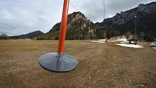 Teller eines Schleppliftes baumeln unbesetzt an einer Skipiste im bayerischen Schwangau, auf der noch Reste von Kunstschnee zu sehen sind. Teller eines Schleppliftes baumeln unbesetzt an einer Skipiste im bayerischen Schwangau, auf der noch Reste von Kunstschnee zu sehen sind.