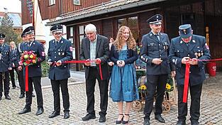 Patenbraut Miriam Kurz durchschneidet zusammen mit Schirmherrn Fischer und den Vorständen der Feuerwehren symbolisch ein Band.