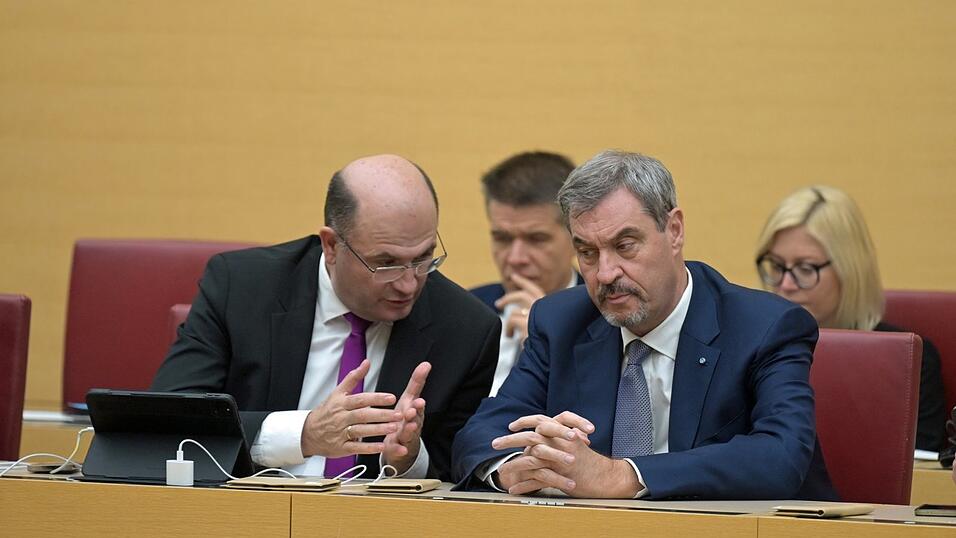 Bayerns Ministerpräsident Markus Söder (r.) bespricht sich bei der Sitzung des bayerischen Landtags mit seinem Finanzminister Albert Füracker.
