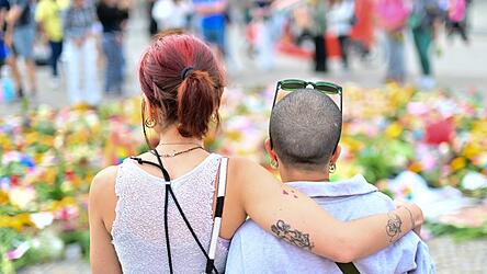 Menschen stehen an Beileidsbekundungen Blumen, Flaggen und Kerzen, die vor dem Brandenburger Tor abgelegt wurden.