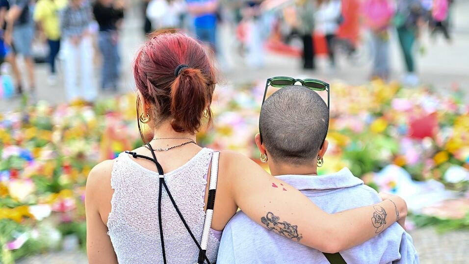 Menschen stehen an Beileidsbekundungen Blumen, Flaggen und Kerzen, die vor dem Brandenburger Tor abgelegt wurden.