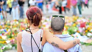 Menschen stehen an Beileidsbekundungen Blumen, Flaggen und Kerzen, die vor dem Brandenburger Tor abgelegt wurden.
