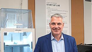 Professor Sean Patrick Saßmannshausen mit einem Bauteil, das in den 3-D-Druckern hinter ihm im „Makerspace“, der Gründerwerkstatt, generiert worden ist.