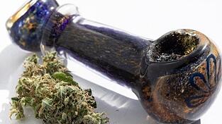 Cannabis liegt neben einer Pfeife. Die Bundesdrogenbeauftragte Daniela Ludwig hat vorgeschlagen, den Besitz kleinerer Mengen an Cannabis nicht mehr strafrechtlich zu verfolgen (Symbolbild).