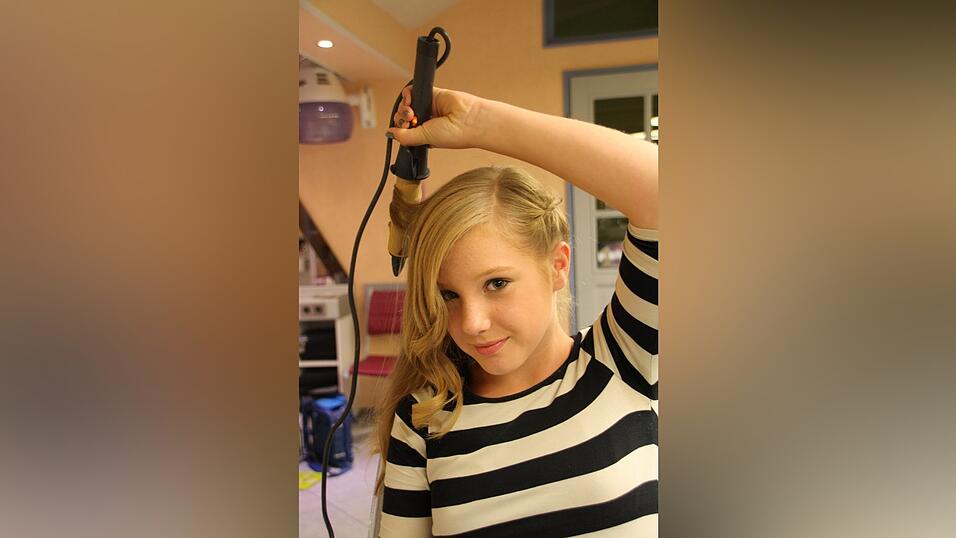 Auch diese Frisur kann, je nach Geschmack, mit einer Blumenspange aufgepeppt werden.3. Den restlichen Haaren gibt sie mit einem Lockenstab (funktioniert auch mit einem Gl&auml;tteisen) einen leichten Schwung nach au&szlig;en, ebenso der Ponypartie. Alternativ k&ouml;nnte sie ihre Haare auch gl&auml;tten.