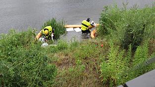 Zwei Feuerwehrleute errichten am Überlauf des Regenrückhaltebeckens am Floßhafen Ölsperren. Zwei Feuerwehrleute errichten am Überlauf des Regenrückhaltebeckens am Floßhafen Ölsperren.
