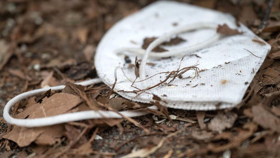 Eine FFP2-Maske liegt zwischen Pflanzenresten. Während der Corona-Pandemie war es teilweise Pflicht, eine solche Maske zu tragen.