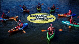 Greenpeace fordert bei einer Aktion am Veranstaltungsort die Abkehr von fossilen Energien.