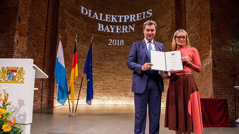 Mit Auszeichnungen geht es weiter. Hier ist Monika Gruber bei der Übergabe des Dialektpreises auf der Bühne zusammen mit dem Bayerischen Ministerpräsidenten Markus Söder. Der Dialektpreis Bayern 2018 wurde in der Allerheiligen-Hofkirche den Preisträgern übergeben und ehrt besondere Verdienste in der Dialektpflege. Mit Auszeichnungen geht es weiter. Hier ist Monika Gruber bei der Übergabe des Dialektpreises auf der Bühne zusammen mit dem Bayerischen Ministerpräsidenten Markus Söder. Der Dialektpreis Bayern 2018 wurde in der Allerheiligen-Hofkirche den Preisträgern übergeben und ehrt besondere Verdienste in der Dialektpflege.