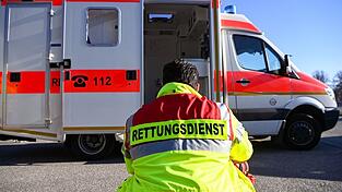 'Rettungsdienst' steht auf der Jacke eines Mannes vor einem Rettungswagen der Feuerwehr.