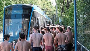 Voll ist es an der Tivolistra&szlig;e. Dutzende Eisbachschwimmer warten auf die n&auml;chste Tram. &bdquo;Normale&ldquo; Fahrg&auml;ste sind an der Haltestelle nur vereinzelt zu finden - viele nehmen das aber mit Humor.