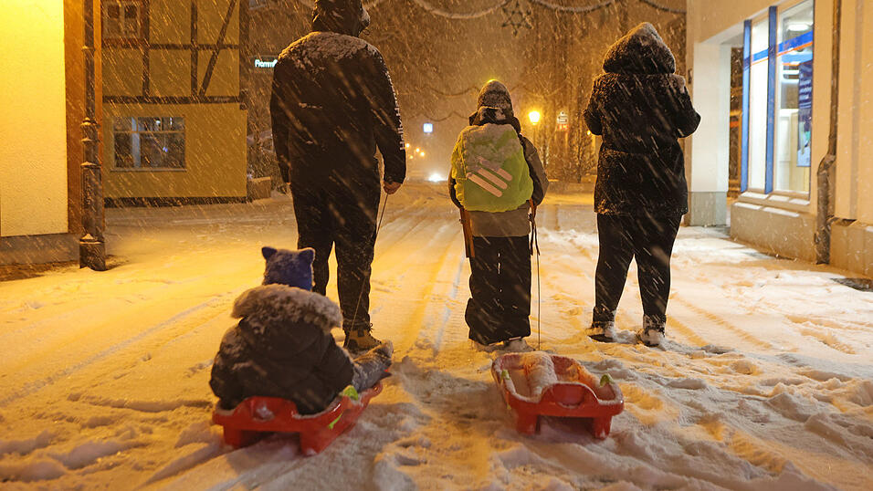 Eltern bringen am fr&uuml;hen Morgen ihre Kinder mit Schlitten in die Schule.