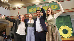 Die beiden Grünen-Landesvorsitzenden Gisela Sengl (links) und Eva Lettenbauer (rechts) nehmen die beiden Hauptredner, die Fraktionsvorsitzende Katharina Schulze und den Bundesvorsitzenden Felix Banaszak, nach deren Auftritt in die Mitte.