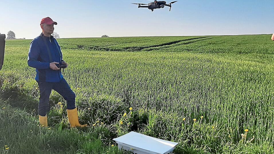 Max Kr&auml;h vom Verein 'Kitzrettung Vilsbiburg' sucht Felder mithilfe einer Drohne nach Wildtieren ab. Vor ihm steht ein Korb mit einem Rehkitz, das er mit der W&auml;rmebildkamera aufsp&uuml;ren konnte. Nach dem M&auml;hen entlassen die Helfer es wieder in die freie Wildbahn.