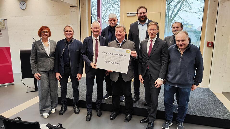 Staatsminister Christian Bernreiter (5.v.l.) &uuml;bergab zusammen mit Vertretern von Land- und Bezirkstag den F&ouml;rderbescheid. OB Markus Pannermayr (3.v.l) und Vertreter von st&auml;dtischen &Auml;mtern nahmen ihn entgegen. Gastgeber war Prof. Dr. Martin Balle (r.) in der neuen Attenkofer-Akademie.