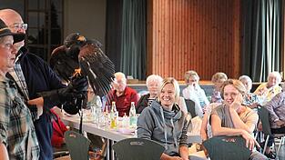 Die Besucher des Seniorennachmittags beobachten den Wüstenbussard fasziniert.
