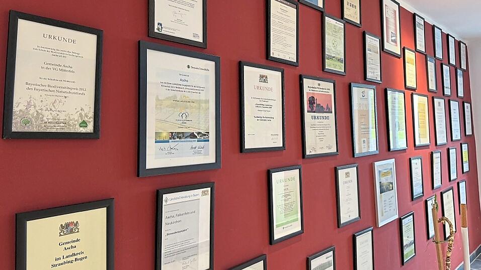 Die Wand am Eingang des Gemeindehauses ist voll mit Urkunden und Zertifikaten. Denn in Ascha wird viel Wert auf Nachhaltigkeit gelegt. Die Wand am Eingang des Gemeindehauses ist voll mit Urkunden und Zertifikaten. Denn in Ascha wird viel Wert auf Nachhaltigkeit gelegt.