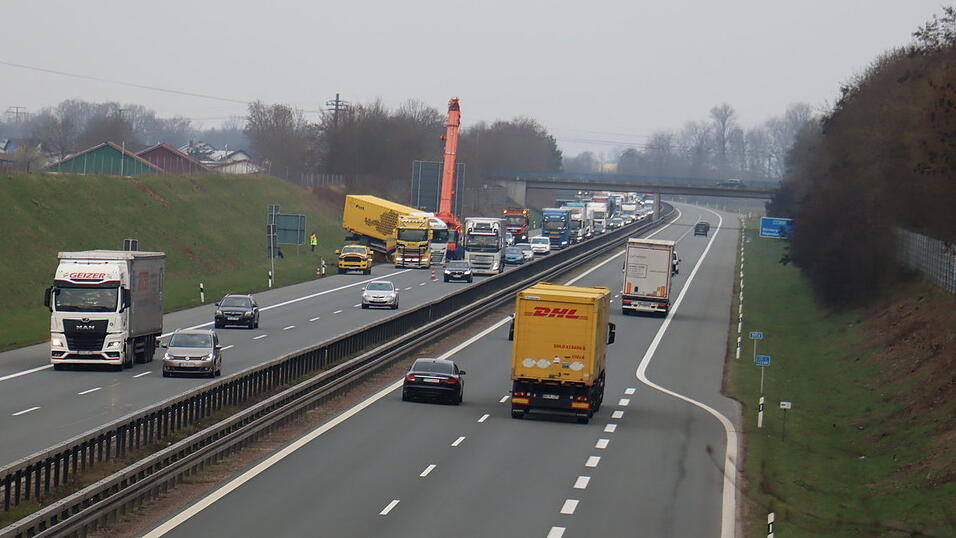 Der Mobilkran bringt sich für die Bergung in Position. Mit schwerem Gerät soll der umgekippte Anhänger gedreht und zurück auf die Fahrbahn gehoben werden. Der Mobilkran bringt sich für die Bergung in Position. Mit schwerem Gerät soll der umgekippte Anhänger gedreht und zurück auf die Fahrbahn gehoben werden.