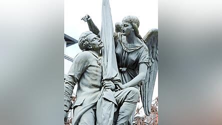 Anscheinend ein Fan von Per&uuml;cken, Schnauzbart und Gehrock, das war die M&auml;nnermode vor 150 Jahren, war der K&uuml;nstler, der B&uuml;rgerdenkmal und Kriegerdenkmal fertigte, die sich sehr &auml;hneln. Hauptunterschied: Einmal h&auml;lt die Bavaria (siehen nebenstehnder Artikel) den Straubinger Helden, einmal ein Engel.