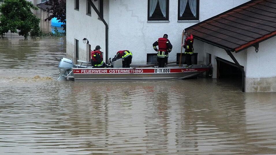 Feuerwehrleute fahren am 1.06.2016 auf der Suche nach Hilfsbed&uuml;rftigen mit einem Boot durch Simbach am Inn.