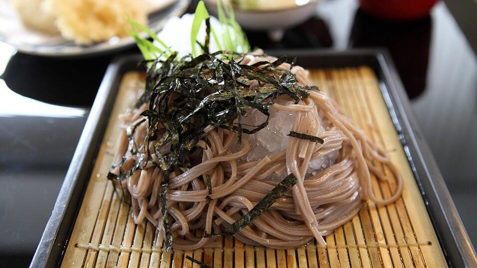 Die grau-braunen Soba-Nudeln aus Japan haben ihre Farbe aufgrund einer wichtigen Zutat. Sie sind im besten Fall komplett aus Buchweizen und somit glutenfrei. Für die Japaner sind sie eine Art Nationalgericht. In der Silvesternacht ist es in Japan üblich, 'Toshikoshi-Soba' ('Soba zum Übergang in das Jahr') zu essen. Laut der japanischen Botschaft hängt dieser Brauch mit dem Glauben zusammen, dass das Essen langer Nudeln eine Garantie für ein langes Leben sei. Und Soba-Nudeln sind durchaus länglich und sehr schmal.