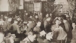 Amerikanische Soldaten feiern Weihnachten 1945 im beschlagnahmten Caf&eacute; Kr&ouml;nner bei Kerzenschein und Christbaumstimmung.